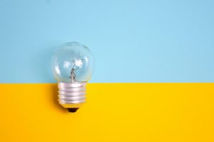 picture of an off lightbulb on a yellow and blue background to talk abbout utility bills.